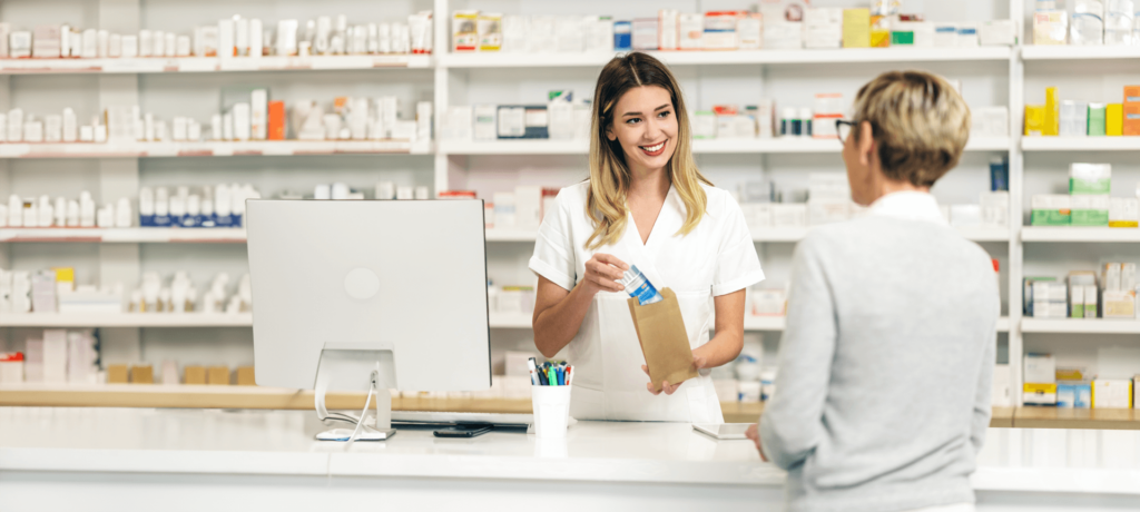 Eine Angestellte in der Apotheke verkauft eine Packung Lactrase®. Bereits seit über 20 Jahren erhalten Sie Lactrase® in der Apotheke.