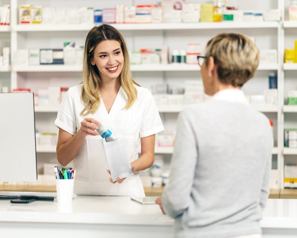 Eine Angestellte in der Apotheke verkauft eine Packung Lactrase®. Bereits seit über 20 Jahren erhalten Sie Lactrase® in der Apotheke.